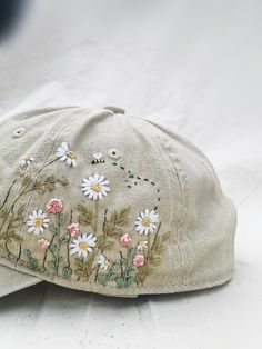 a baseball cap with daisies on it sitting on a white tablecloth covered surface