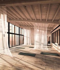 an empty room with yoga mats on the floor and sheer curtains hanging from the ceiling