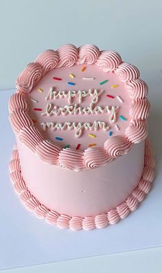 a pink birthday cake with sprinkles and the words happy birthday on it