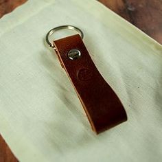 a brown leather keychain sitting on top of a wooden table