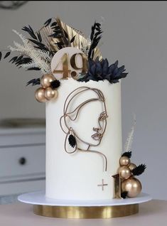 a white cake decorated with gold and black decorations on top of a table next to a clock