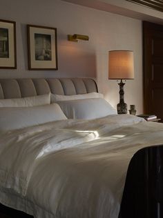 a bed with white sheets and pillows in a bedroom