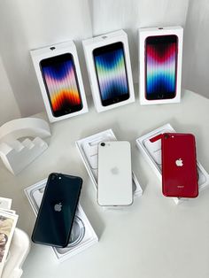 three iphones are sitting in their boxes on the table next to some other items