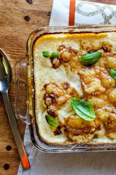 a casserole dish with meat, cheese and basil garnish on top