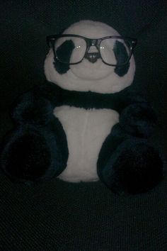 a stuffed panda bear wearing glasses sitting on a chair