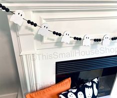 a fireplace decorated for halloween with black and white paper ghost garland on the mantel