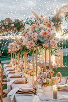 a table set up with flowers and candles for an outdoor wedding reception in the evening