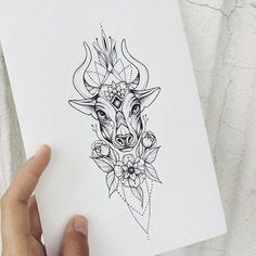 a person holding up a piece of paper that has a bull's head on it