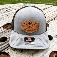 a gray and black trucker hat sitting on top of a wooden table next to some logs