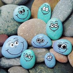 some rocks with faces painted on them are sitting in the middle of a pile of stones