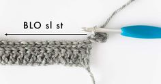 the crochet stitch is being worked on with a blue handled knitting needle and thread