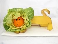 a stuffed animal that is laying down next to a head of lettuce and a banana