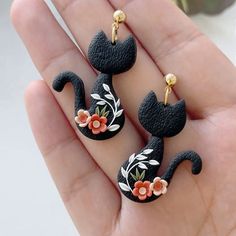 two black cat shaped earrings with flowers on them