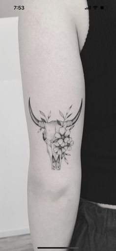 a black and white photo of a bull skull with flowers