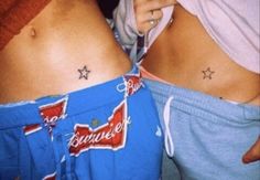 two women with matching tattoos on their stomachs, one is holding a cell phone