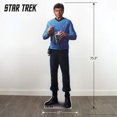 a man standing in front of a star trek poster holding a camera and wearing black rubber boots