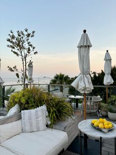 an outdoor seating area with umbrellas and lemons on the table, overlooking the ocean