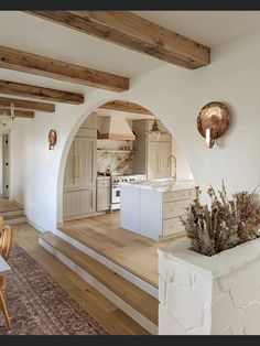 a kitchen with an archway leading to the living room and dining area is shown in this image