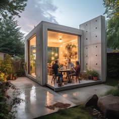 two people sitting at a table in the back of a small house with glass walls