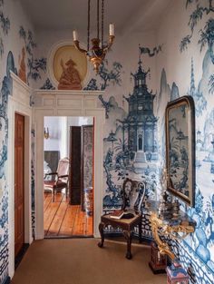 the hallway is decorated with blue and white wallpaper, an ornate chandelier and antique furniture