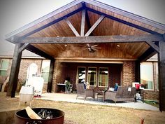 a covered patio with chairs and a ceiling fan in the middle of it's back yard