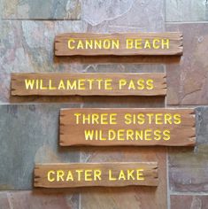 three wooden signs that are on the side of a stone wall with words written below them