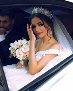 a bride sitting in the back seat of a car with her hand up to her face