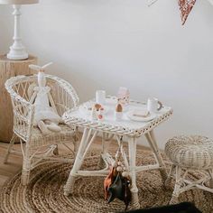 a wicker table and chairs in a white room with bunting flags on the wall