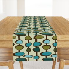 a wooden table topped with a blue, green and brown patterned table runner on top of it