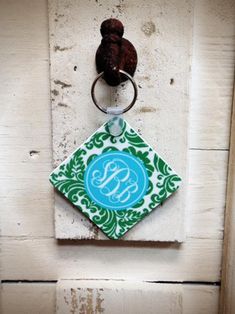 a keychain hanging on the side of a door with a monogram design