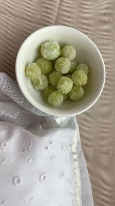 a white bowl filled with powdered sugar covered donuts on top of a table