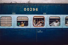 people are sitting in the windows of a train car that is painted blue and has numbers on it