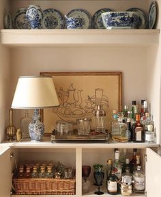 a shelf filled with bottles and glasses next to a lamp