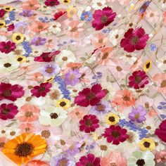 an image of colorful flowers on white fabric with orange and pink flowers in the middle