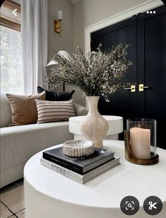 a white coffee table topped with books and a vase filled with flowers on top of it