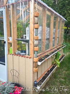 a small greenhouse with lots of plants growing in it and the roof is made out of wood