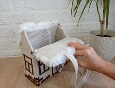 a hand is holding the inside of a small house made out of felt and fabric