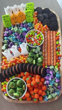 a tray filled with halloween treats and candies on top of a wooden table next to candy