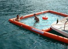 two people in an inflatable raft floating on the water next to a boat