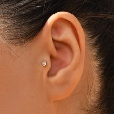 a woman's ear is shown with a single diamond in the middle of it