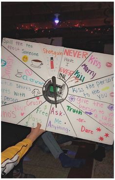 a person holding up a large white board with writing on it in front of a crowd