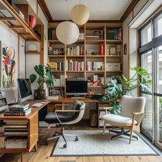 a home office with bookshelves, desk and chair in front of large windows