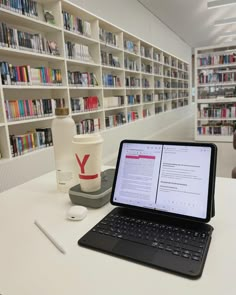 an open laptop computer sitting on top of a table in front of a book shelf