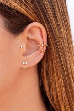 a woman wearing three different types of ear piercings