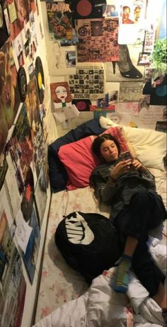 a woman laying on top of a bed next to a wall covered in pictures and posters