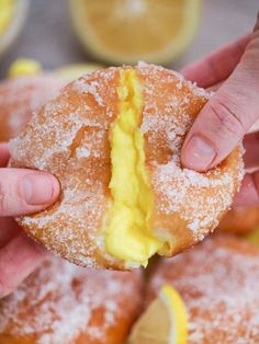 a person is holding a powdered sugar doughnut with lemon on the side and it has a bite taken out