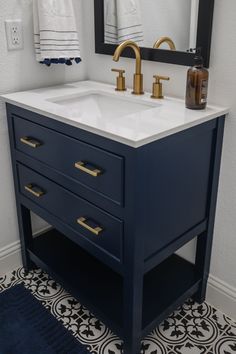 a bathroom sink with two gold faucets and a mirror above it on the wall