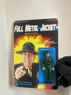 the action figure is being held up by someone's hand and wearing black gloves