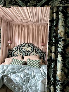 a bed with a canopy over it in a room filled with curtains and pillows on top of it