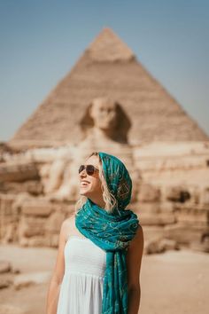 a woman wearing sunglasses standing in front of the pyramids at giza, egypt